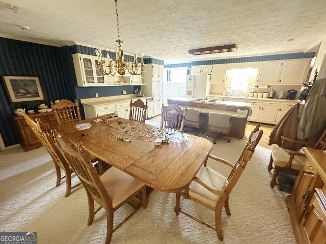 dining area with a chandelier, a textured ceiling, and light carpet