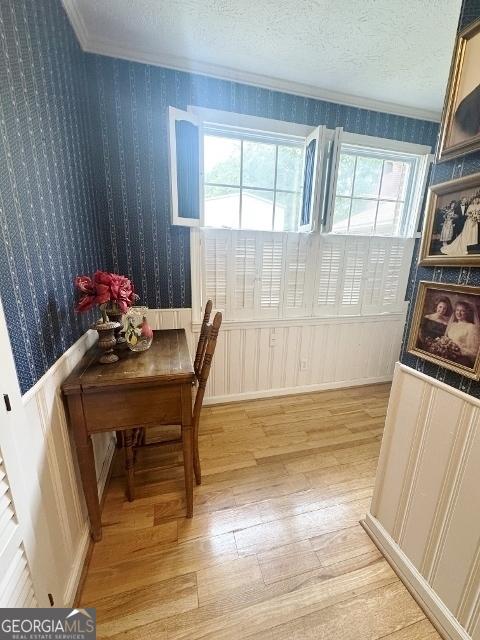 dining room featuring light wood-type flooring, wallpapered walls, a wealth of natural light, and ornamental molding