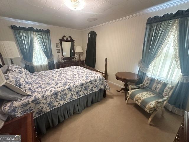 bedroom with ornamental molding and light carpet