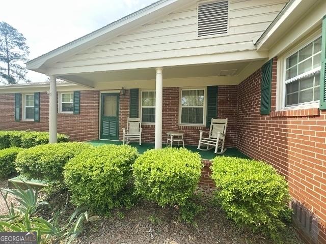 entrance to property with covered porch and brick siding