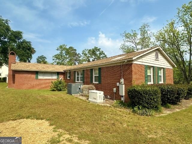 back of property featuring brick siding, a yard, and cooling unit