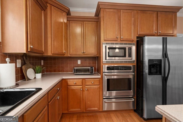 60 Heritage Keep, Covington, GA 30016 - kitchen with appliances with stainless steel finishes, a warming drawer, brown cabinetry, and crown molding
