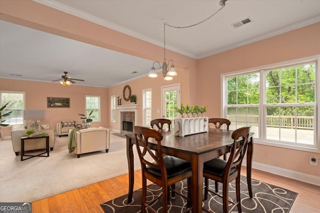 60 Heritage Keep, Covington, GA 30016 - dining area featuring healthy amount of natural light, ornamental molding, light wood-type flooring, a fireplace, and ceiling fan