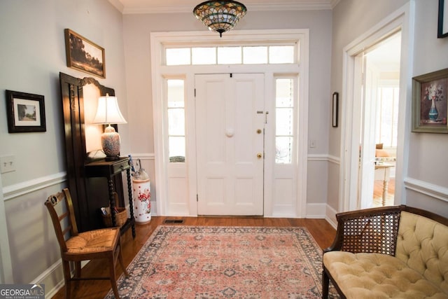 entryway with wood finished floors and ornamental molding