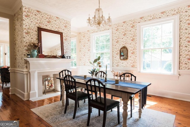dining area featuring ornamental molding, wallpapered walls, wainscoting, a chandelier, and wood finished floors