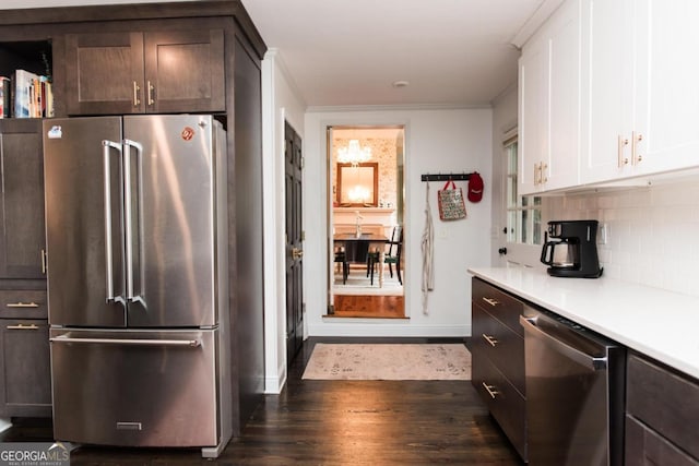 kitchen featuring appliances with stainless steel finishes, light countertops, dark wood-type flooring, backsplash, and white cabinets