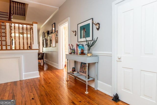 corridor featuring wood finished floors, baseboards, and ornamental molding