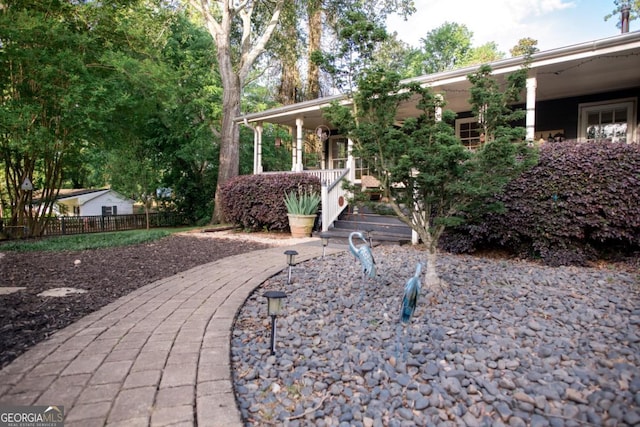 view of yard with covered porch and fence