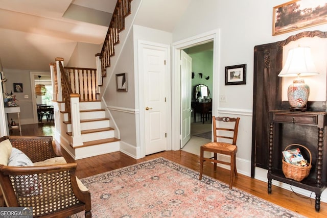 foyer featuring vaulted ceiling, wood finished floors, stairway, and baseboards