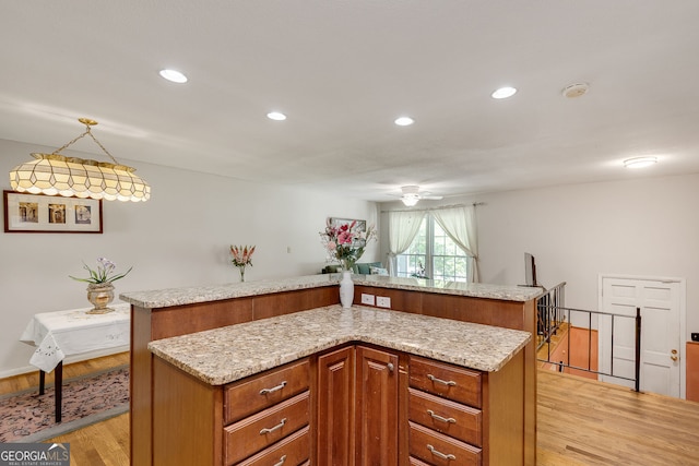 kitchen featuring light wood-style flooring, a center island, a ceiling fan, brown cabinetry, and recessed lighting
