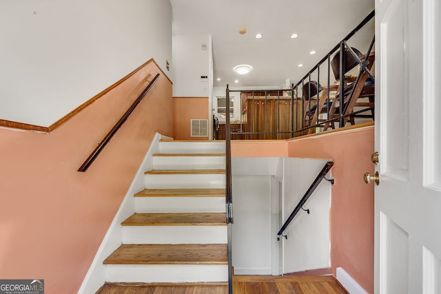stairs with wood finished floors, recessed lighting, and baseboards