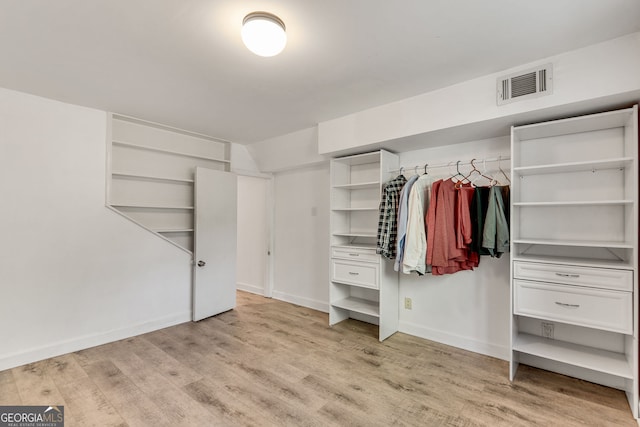 walk in closet with light wood finished floors