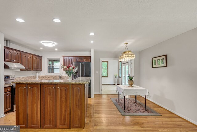 3990 Admiral Dr, Chamblee, GA 30341 - kitchen with under cabinet range hood, stainless steel electric stove, light wood-style flooring, light stone countertops, and a kitchen island