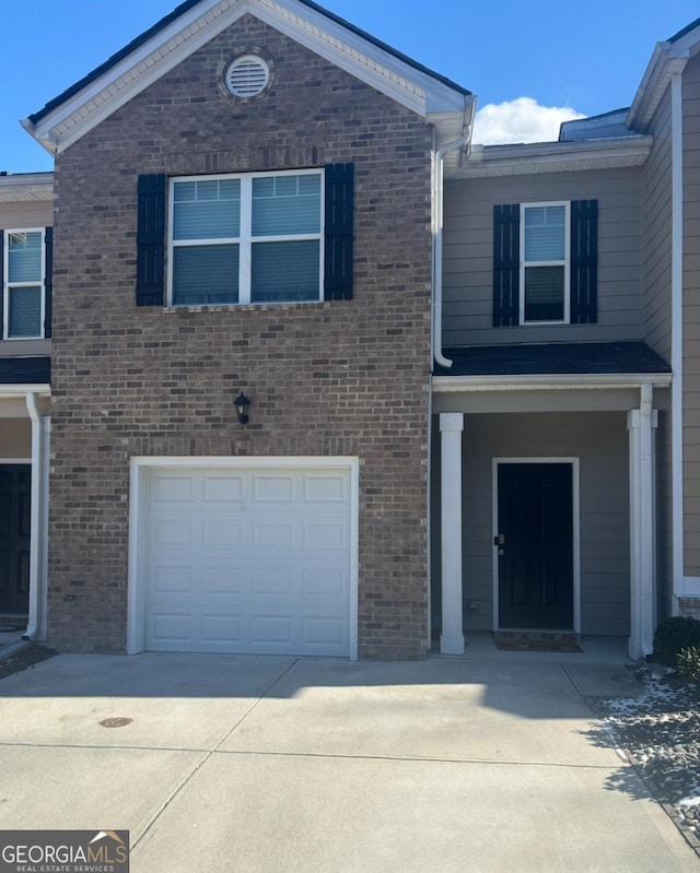view of front facade featuring an attached garage, driveway, and brick siding