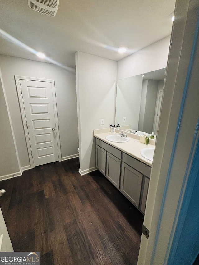 bathroom with wood finished floors, double vanity, and baseboards