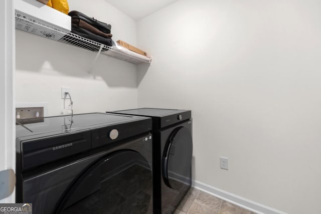 clothes washing area with washing machine and clothes dryer, laundry area, and baseboards