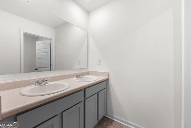 bathroom featuring baseboards, a sink, and double vanity