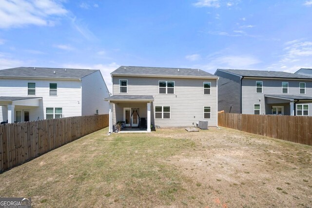back of house featuring a patio, a fenced backyard, a yard, and central AC unit