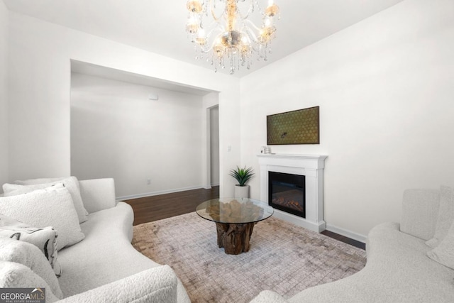 living room featuring a chandelier, a glass covered fireplace, wood finished floors, and baseboards
