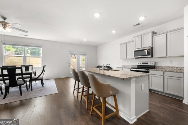 kitchen featuring a sink, a center island with sink, visible vents, a ceiling fan, and appliances with stainless steel finishes