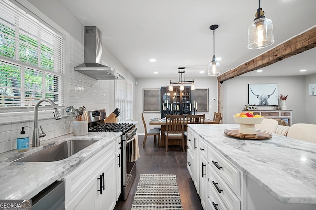 kitchen featuring recessed lighting, wall chimney range hood, a sink, decorative backsplash, and appliances with stainless steel finishes