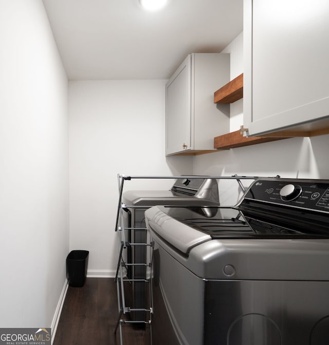 laundry area with baseboards, dark wood-style flooring, washer and clothes dryer, and cabinet space