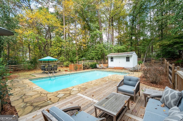 view of swimming pool featuring a deck, a fenced backyard, outdoor dining area, an outbuilding, and a fenced in pool