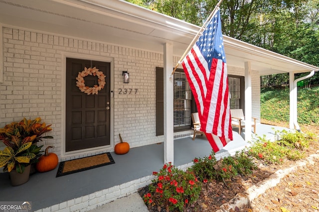 property entrance featuring brick siding and a porch
