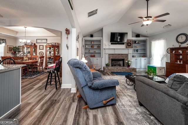 99 Mcmillian Ct, Winder, GA 30680 - living room featuring a brick fireplace, wood finished floors, visible vents, and ceiling fan with notable chandelier