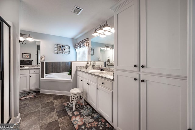 99 Mcmillian Ct, Winder, GA 30680 - bathroom with visible vents, two vanities, a garden tub, and a sink