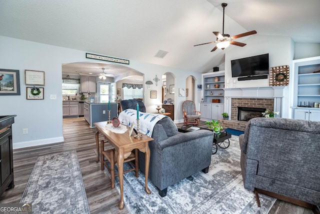99 Mcmillian Ct, Winder, GA 30680 - living area with dark wood finished floors, vaulted ceiling, visible vents, a ceiling fan, and a fireplace