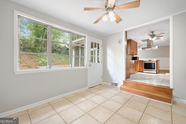 interior space with baseboards, a ceiling fan, visible vents, and light tile patterned floors