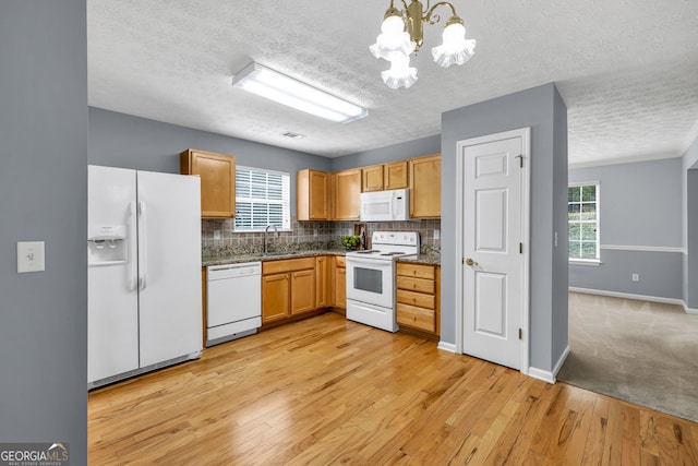 1220 Skipping Rock Ln SW, Grayson, GA 30017 - kitchen featuring light wood-style floors, white appliances, a textured ceiling, a chandelier, and tasteful backsplash