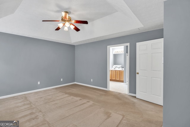 1220 Skipping Rock Ln SW, Grayson, GA 30017 - unfurnished bedroom featuring ceiling fan, a raised ceiling, baseboards, ensuite bathroom, and light carpet