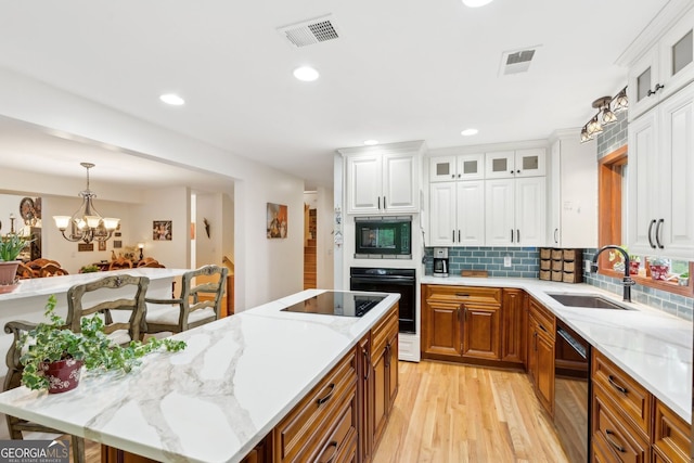 4761 Gateway Ln, Flowery Branch, GA 30542 - kitchen featuring black appliances, light wood-style floors, a kitchen island, white cabinetry, and recessed lighting