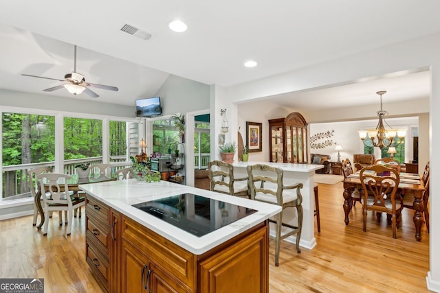 kitchen with brown cabinets, visible vents, light countertops, open floor plan, and black electric cooktop