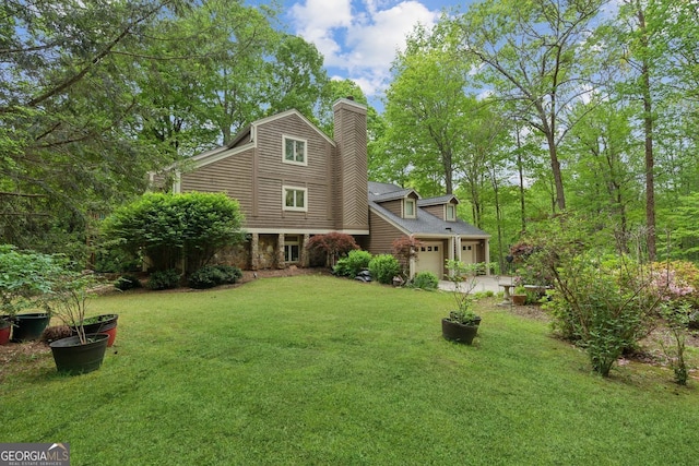 4761 Gateway Ln, Flowery Branch, GA 30542 - rear view of house featuring an attached garage, a lawn, a chimney, and stone siding