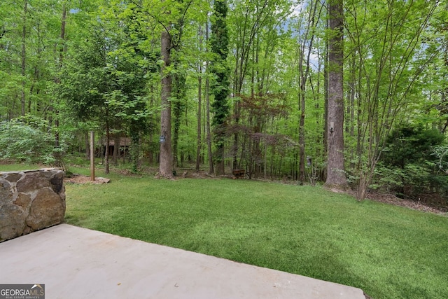 view of yard featuring a patio area and a view of trees
