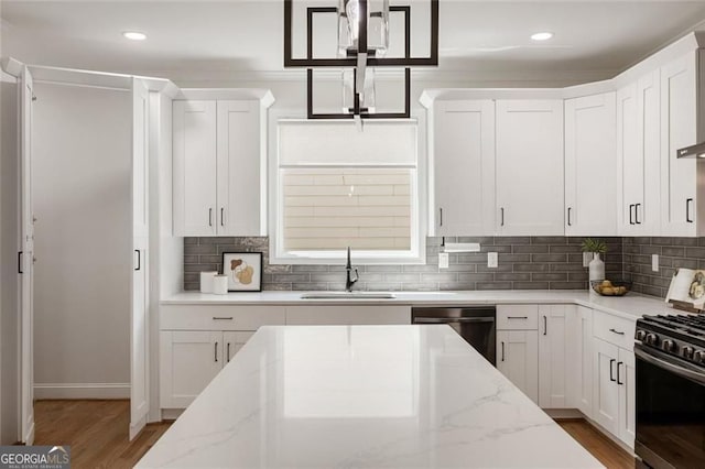 2553 Creekwood Ter, Decatur, GA 30030 - kitchen with stainless steel appliances, a sink, light wood-style flooring, white cabinetry, and decorative backsplash