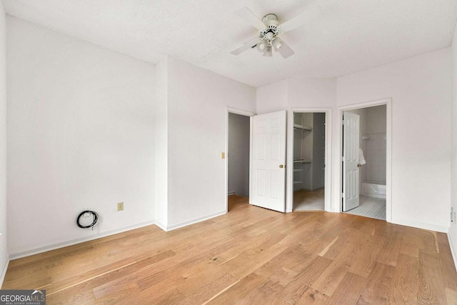 406 Vinings Forest Cir SE, Smyrna, GA 30080 - unfurnished bedroom with light wood finished floors, a walk in closet, baseboards, ceiling fan, and ensuite bathroom