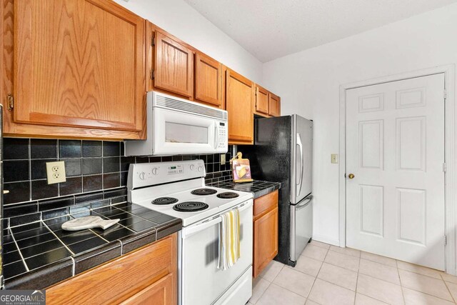 406 Vinings Forest Cir SE, Smyrna, GA 30080 - kitchen featuring tile counters, brown cabinets, white appliances, light tile patterned flooring, and tasteful backsplash