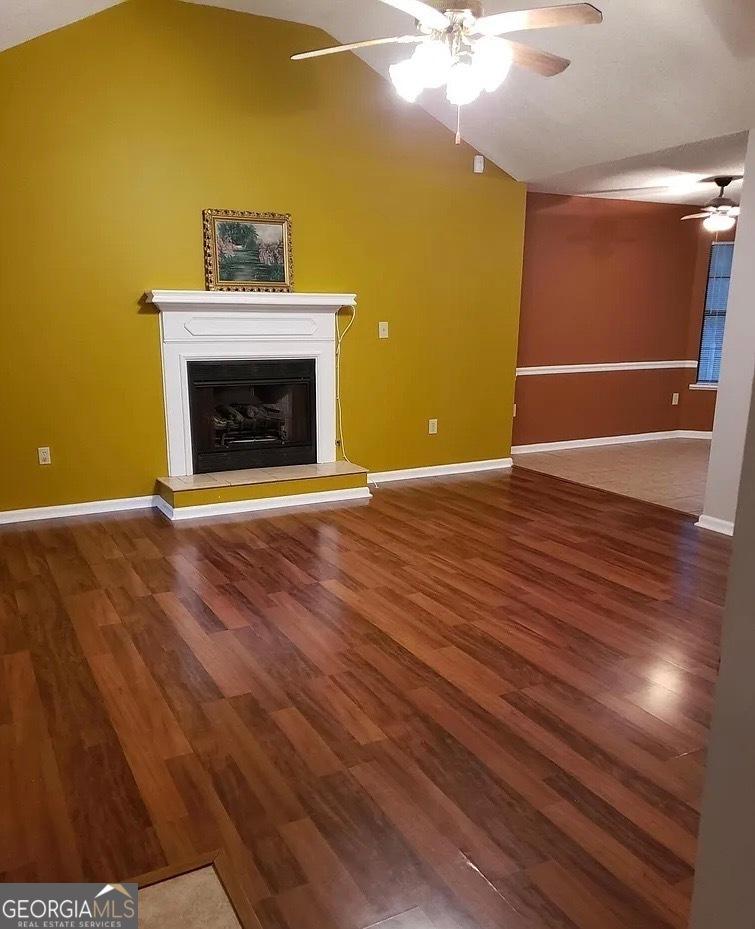 1303 Saddle Horn Dr, Macon, GA 31220 - unfurnished living room featuring lofted ceiling, ceiling fan, wood finished floors, and a fireplace with raised hearth