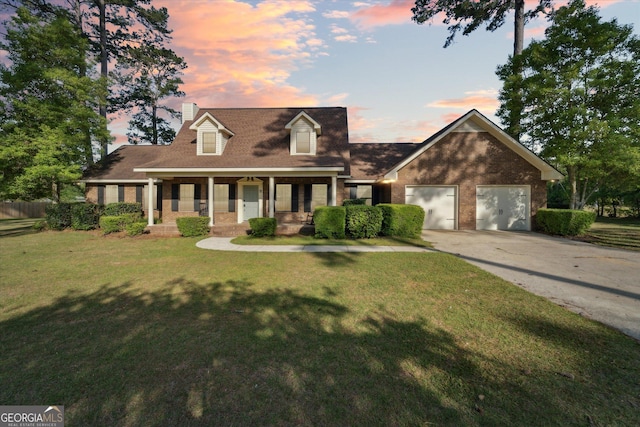 new england style home with a front lawn, a porch, concrete driveway, brick siding, and an attached garage