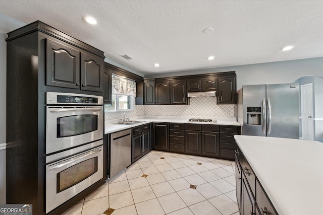 kitchen featuring light countertops, a sink, appliances with stainless steel finishes, and tasteful backsplash