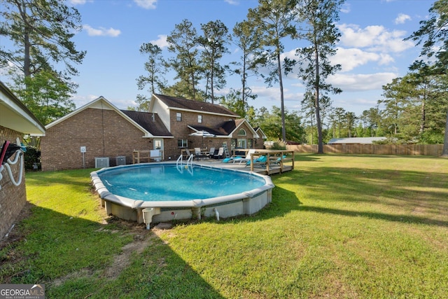 view of swimming pool featuring central AC, fence, a fenced in pool, and a lawn