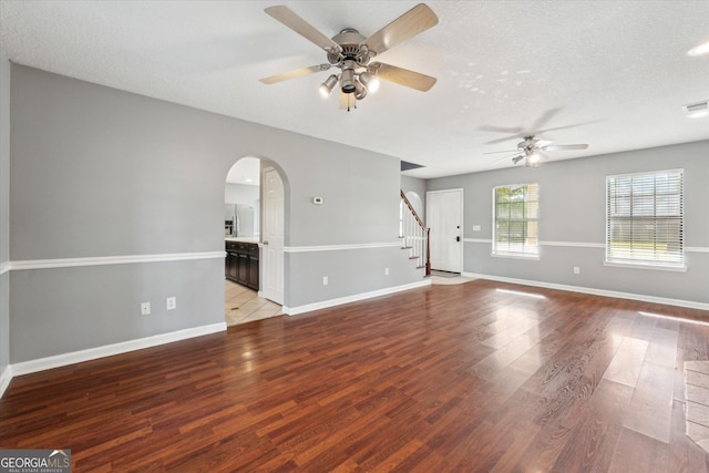 unfurnished room with light wood-style flooring, arched walkways, stairs, and ceiling fan