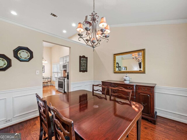 2402 Jasmine Glen Dr, Buford, GA 30519 - dining area with crown molding, a chandelier, wainscoting, a decorative wall, and wood finished floors