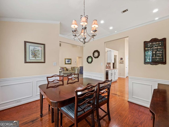 2402 Jasmine Glen Dr, Buford, GA 30519 - dining space with a decorative wall, wood finished floors, an inviting chandelier, a wainscoted wall, and ornamental molding