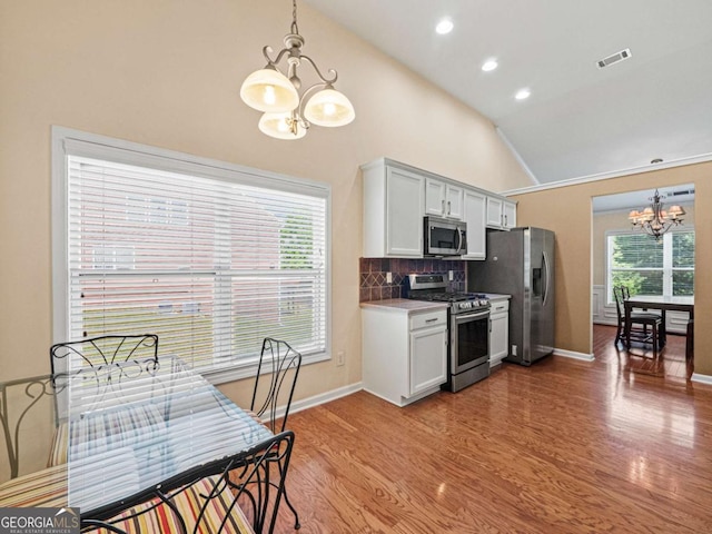 2402 Jasmine Glen Dr, Buford, GA 30519 - kitchen with wood finished floors, a chandelier, stainless steel appliances, lofted ceiling, and visible vents