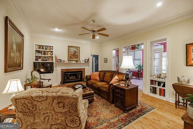 835 Timothy Rd, Athens, GA 30606 - living area featuring light wood finished floors, built in shelves, a ceiling fan, a brick fireplace, and crown molding